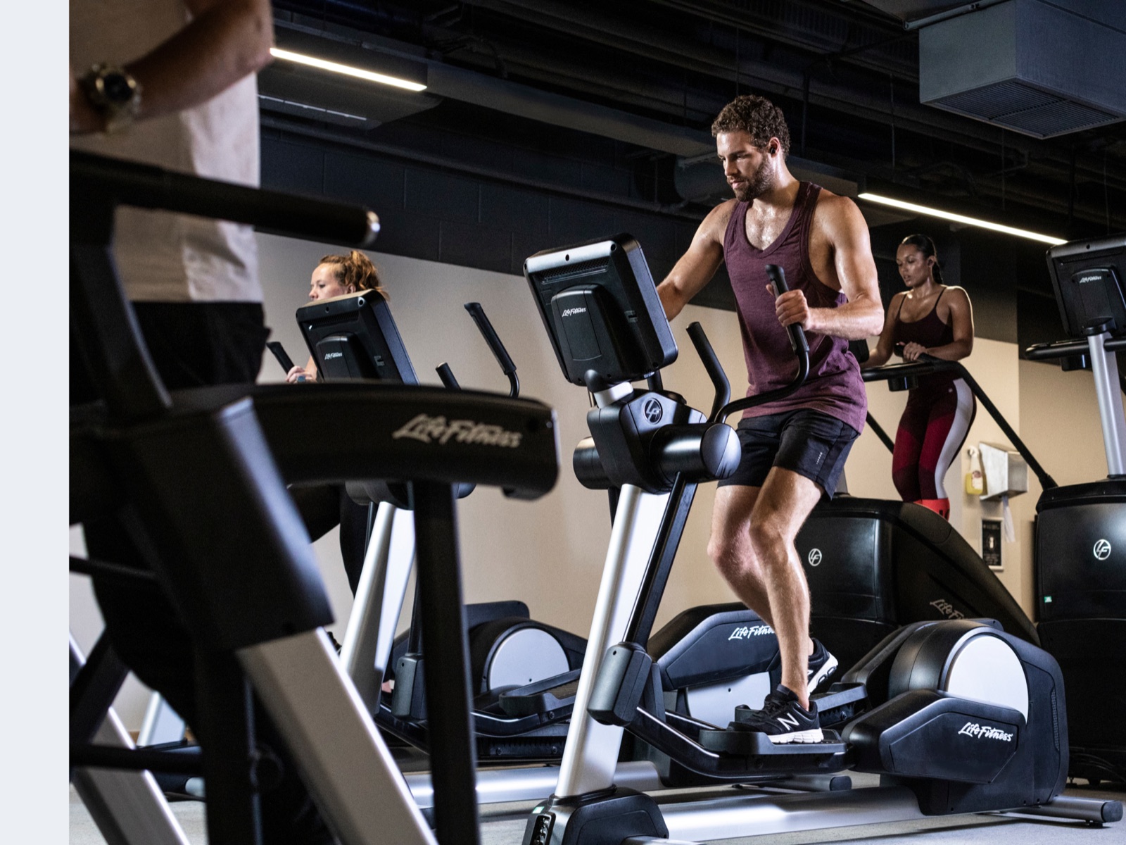 Man running on a Life Fitness treadmill in a busy gym