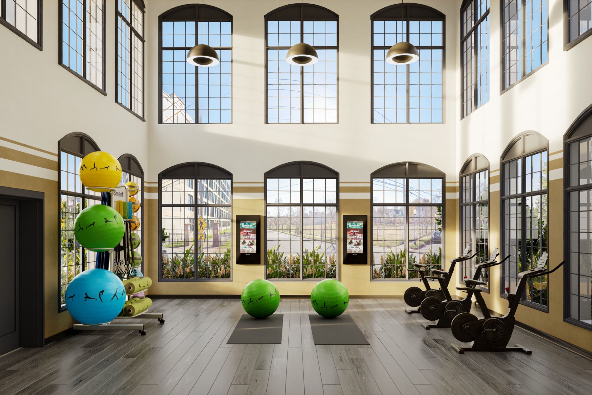 Sunlit fitness center with tall arched windows, exercise balls and cardio equipment