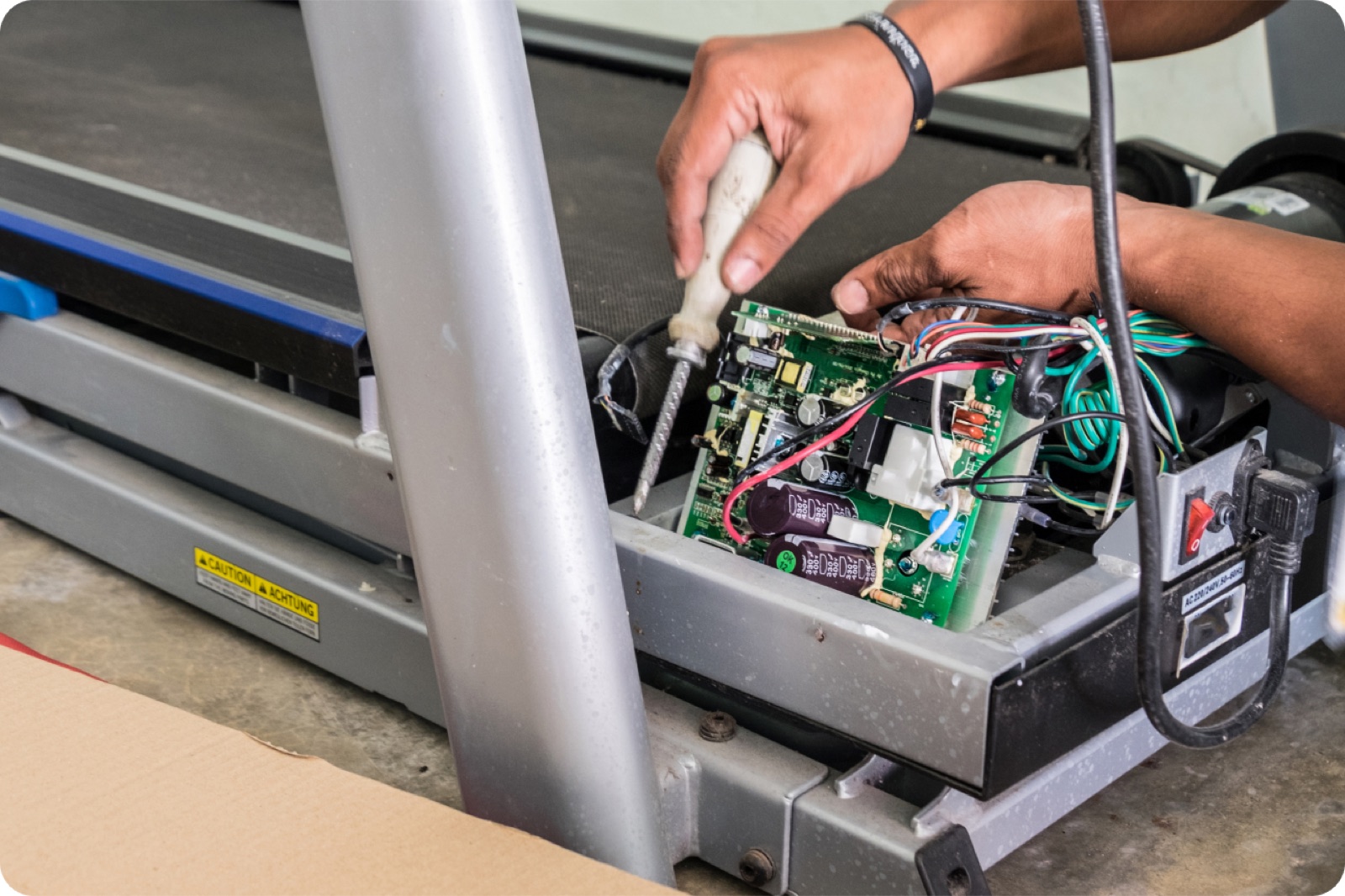 Technician repairing treadmill electronics