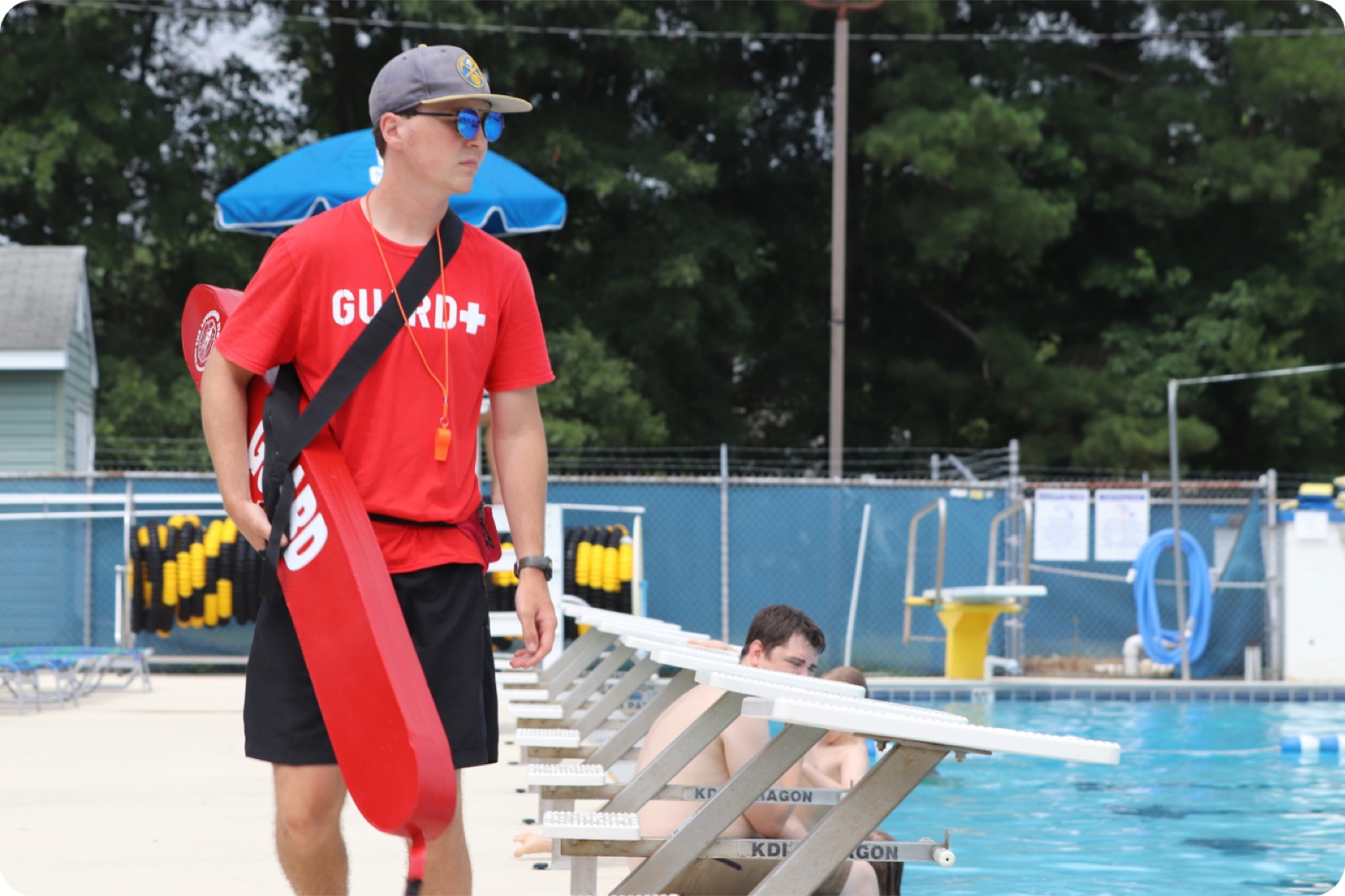 Lifeguard walking along an outdoor pool deck