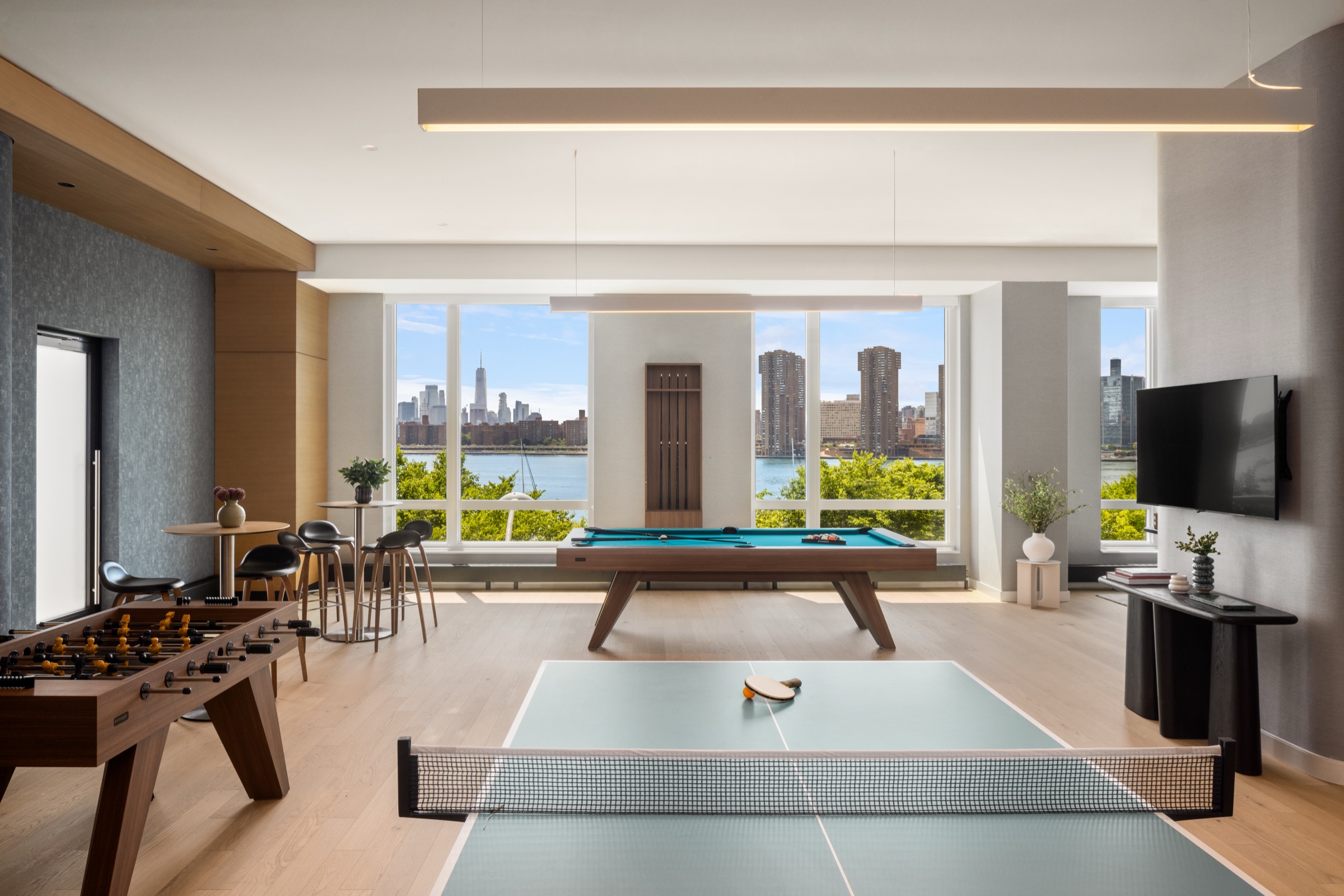 Salon de jeux avec table de billard, baby-foot et ping-pong donnant sur la ville