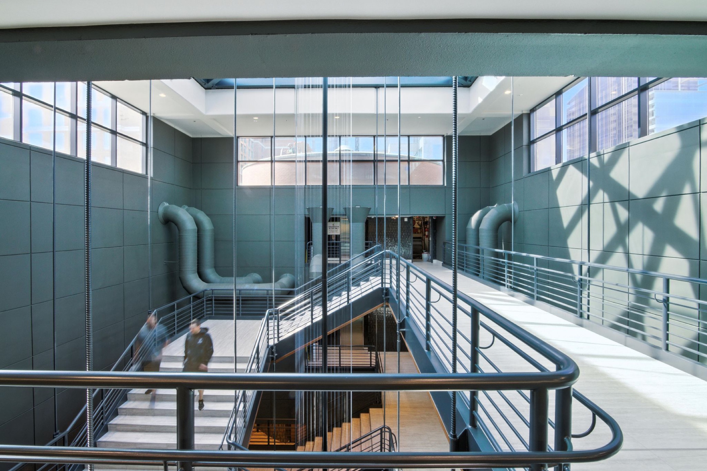 Atrium industriel avec conduits apparents et escalier ouvert