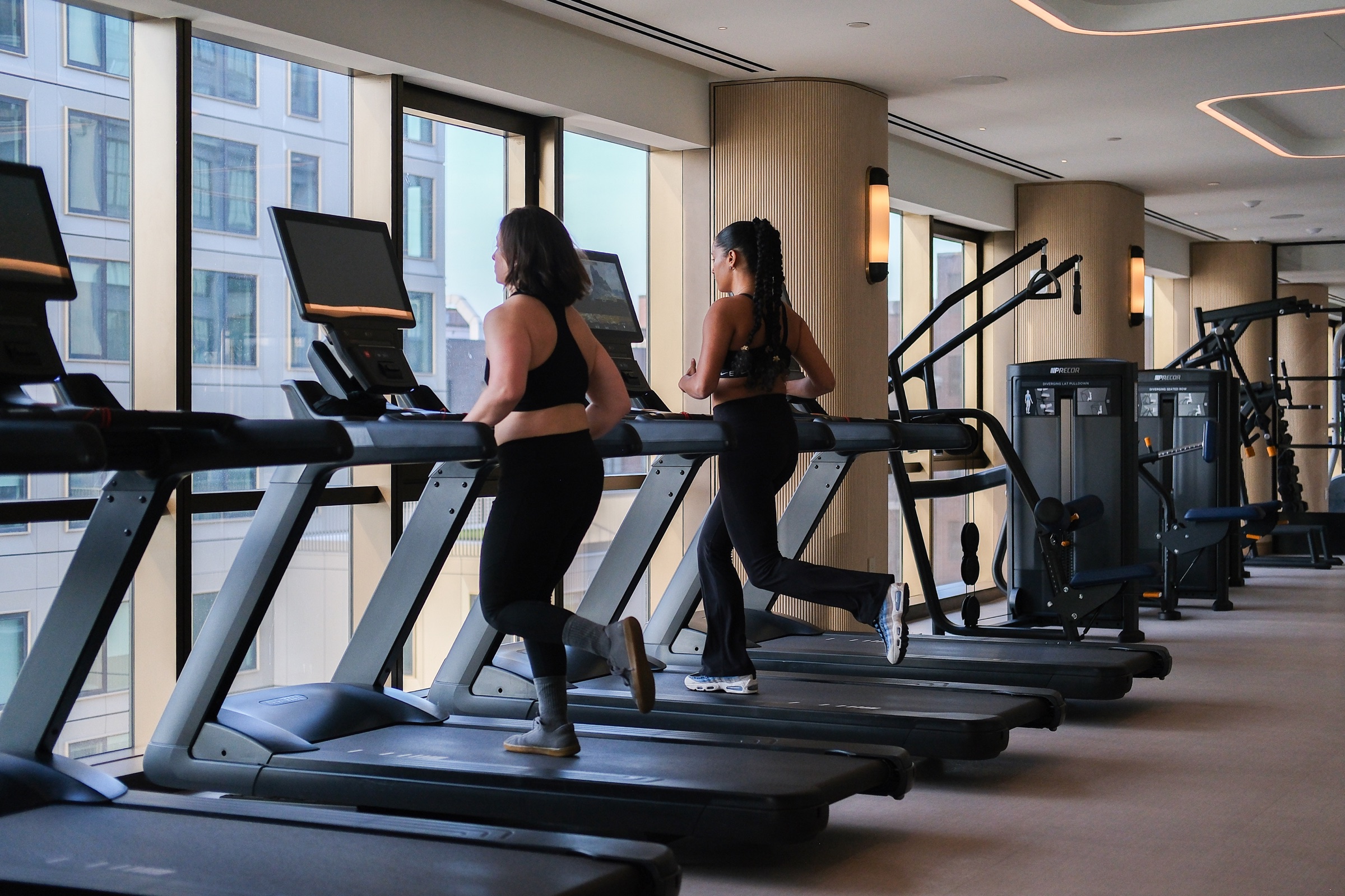 Deux femmes courant sur des tapis roulants dans un centre de conditionnement physique en hauteur